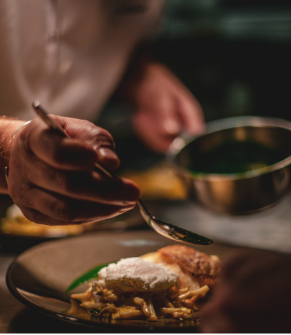 un chef finalise son plat par une sauce à l'huile qui sublimera les saveurs.