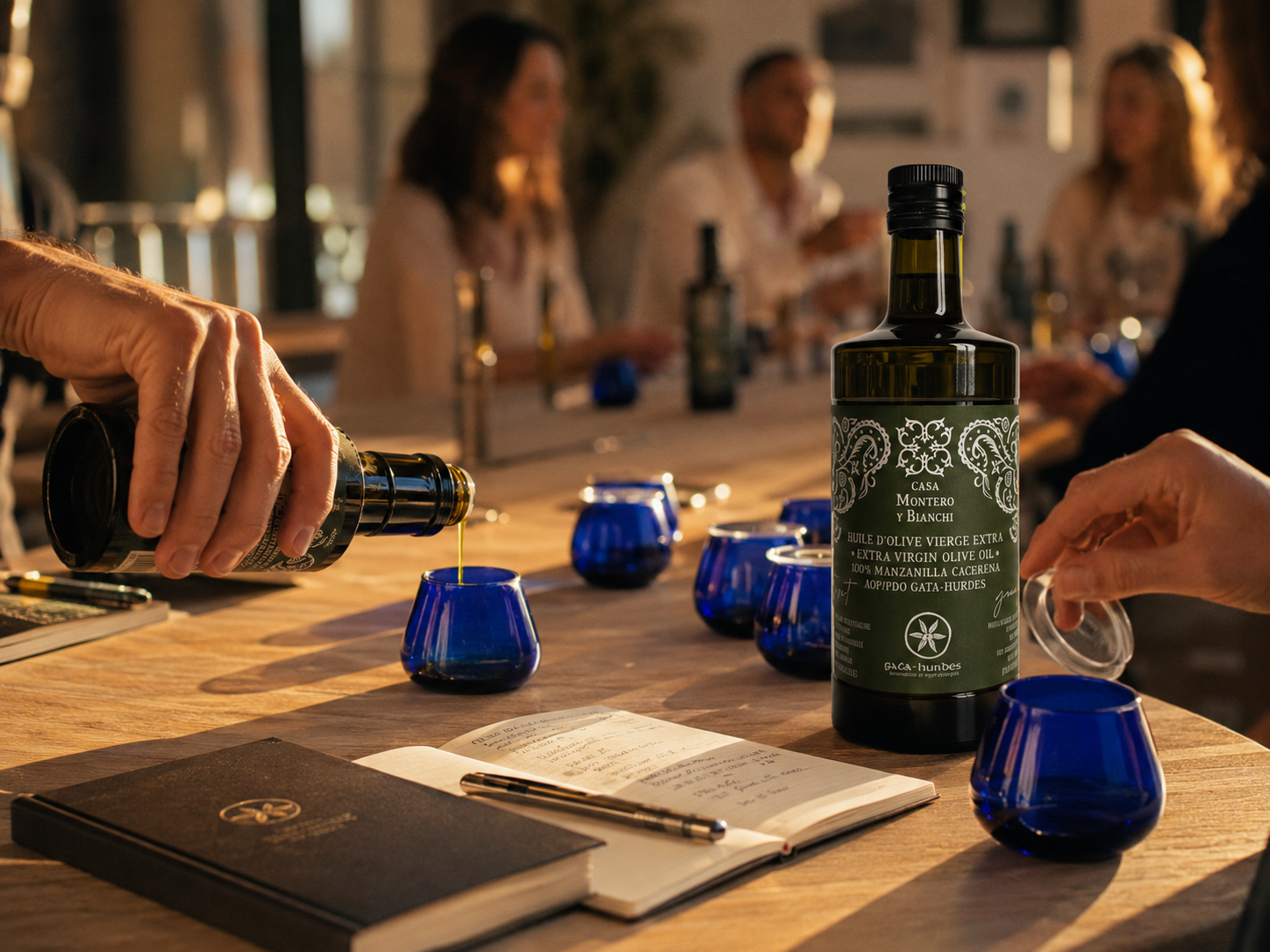 Participants découvrant une huile d'olive vierge extra Casa Montero y Bianchi lors d'un atelier de dégustation avec verres professionnels COI et carnet de dégustation.